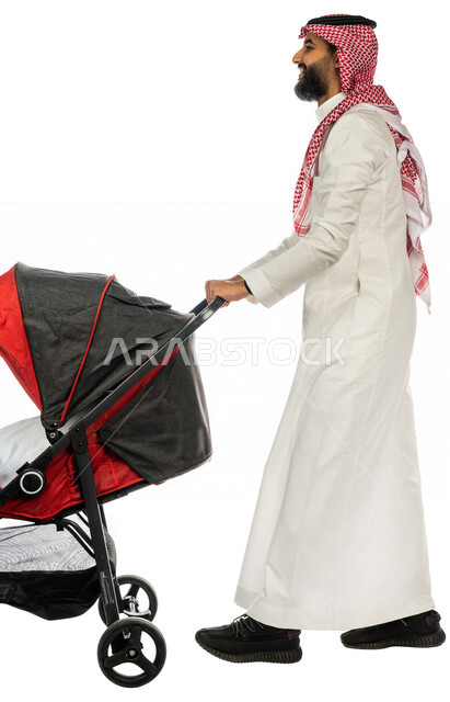 بورتريه من الجانب لرجل عربي خليجي سعودي يجرعربة الأطفال ، رابطة الأبوة ، ترابط عاطفي ، مفهوم الأسرة السعيدة ، نزهة و جولة عائلية ، قضاء أوقات عائلية ممتعة