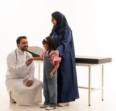 الابقاء على العلاقة الودودة بين المرضى و الاطباء مع الحفاظ على الجدية في أداء المهنة ,طبيب عربي خليجي سعودي يرتدي المعطف الطبي الابيض يجلس القرفصاء امام الطفلة الصغيرة ,طبيبة عربية خليجية سعودية محجبة ترتدي عباءة زرقاء تمسك بالطفلة الصغيرة بعد الانتهاء من الفحص , بورتريه خلفية بيضاء , الجسم بالطول الكامل