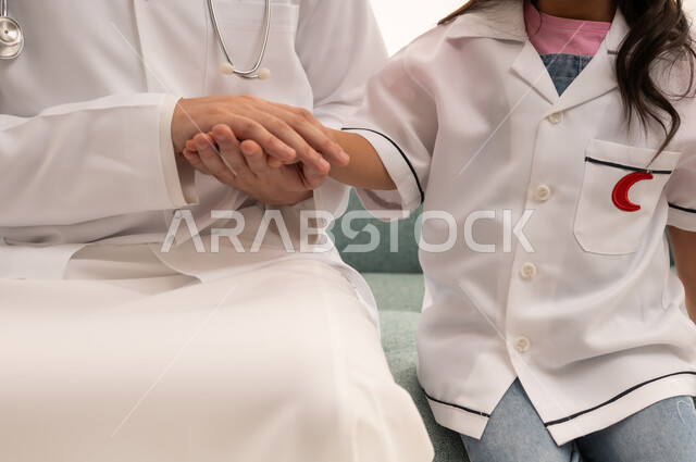 A Saudi Gulf Arab girl is wearing a little doctor's outfit and holding the doctor's hand. A close-up portrait of a Saudi Gulf Arab doctor wearing a white medical coat holding the little hand to ensure her safety, with a white background.