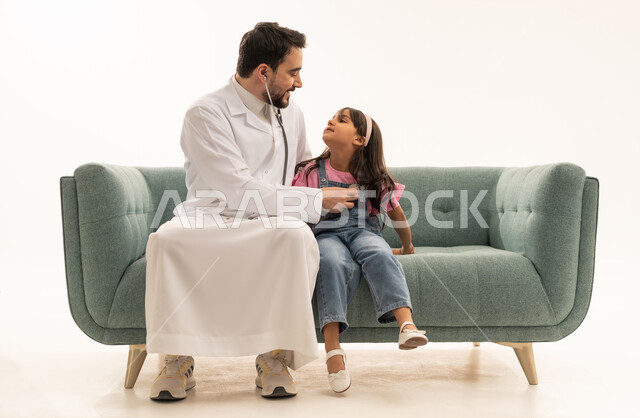 التأكد من سلامة القلب و صحته ,طفلة عربية خليجية سعودية ترتدي الزي الكاجوال تنظر الى الطبيب اثناء الفحوصات الدورية ,طبيب عربي سعودي خليجي يستمع الى نبضات قلب الصغيرة للاطمئنان على صحتها ,بورتريه خلفية بيضاء الجسم بالطول الكامل