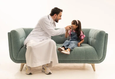 بورتريه خلفية بيضاء الجسم بالطول الكامل , طبيب عربي خليجي سعودي يرتدي المعطف الطبي الابيض يقوم بوضع قناع التنفس للمريضة , طفلة عربية خليجية سعودية ترتدي الزي الكاجوال تجلس على الاريكة , تقديم المساعدة اللازمة بسرعة ,