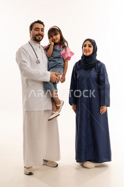 علاقة الود و الثقة المتبادلة بين اطباء هيئة الهلال الاحمر السعودي و المرضى ,طبيب عربي خليجي سعودي يرتدي المعطف الطبي الابيض يحمل طفلة بسعادة و سرور ,طبيبة عربية خليجية سعودية محجبة ترتدي عباءة زرقاي تقف بجانب الطبيب ,ايماءات السعادة و الابتسام ,بورتريه خلفية بيضاء ,الجسم بالطول الكامل