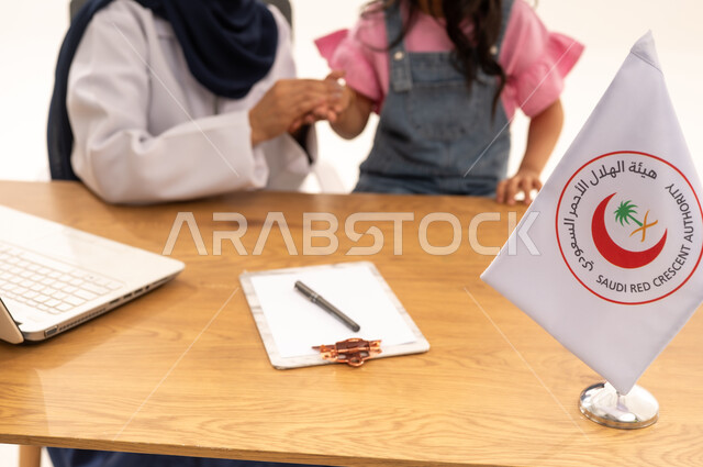 كتابة الوصفات الطبية المناسبة لحالة كل مريض ,بورتريه مقرب لطفلة صغيرة عربية خليجية سعودية ترتدي الزي الكاجوال تمسك يد طبيبة عربية خليجية سعودية للتأكد من سلامتها ,خلفية بيضاء