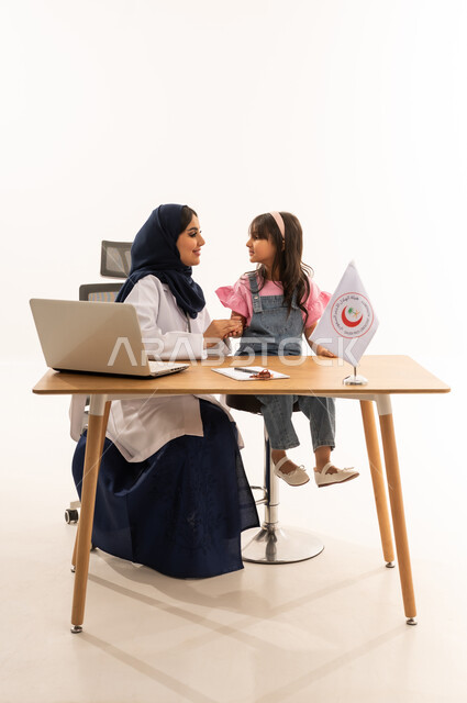 طبيبة عربية خليجية سعودية محجبة ترتدي عباءة زرقاء تنظر للطفلة بابتسامة ودودة ,طفلة عربية سعودية خليجية صغيرة تجلس على الكرسي المقابل للطبيبة و تبتسم بدورهها ,بورتريه خلفية بيضاء الجسم بالطول الكامل ,ايماءات السعادة و الفرحة