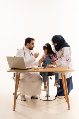 Receiving treatment calmly and safely with qualified and trained medical professionals, an Arab Gulf Saudi doctor wearing a white coat giving a therapeutic injection to a small girl, an Arab Gulf Saudi female doctor in a hijab standing next to the girl to provide a sense of security, full-length portrait with a white background.