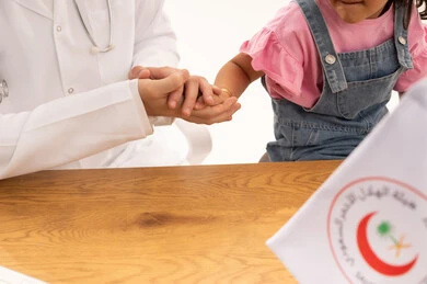 هيئة الهلال الاحمر السعودي رمز للامان و اتقان العمل ,طفلة عربية خليجية سعودية ترتدي الزي الكاجوال تمسك تشعر بالامان مع طبيبها ,طبيب عربي سعودي خليجي يرتدي المعطف الطبي الابيض ,بورتريه مقرب ,خلفية بيضاء