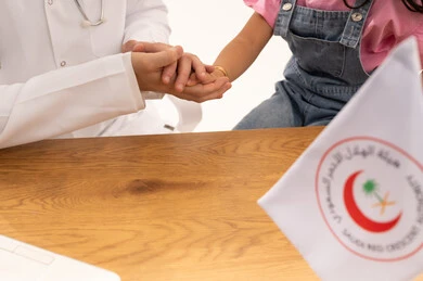 مفهوم السلامة و الامان ,طبيب عربي سعودي خليجي يربت على يد فتاة صغيرة ليطمئنها بعد نهاية الفحص الطبي ,فتاة عربية خليجية سعودية ترتدي الزي الكاجوال ,بورتريه مقرب ,خلفية بيضاء