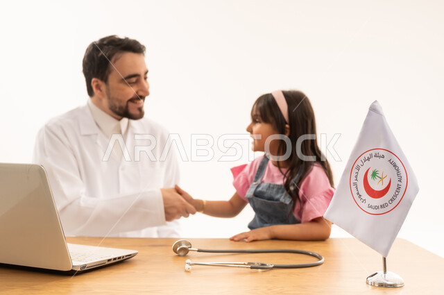 علاقة الود و الثقة المتبادلة بين الطبيب و المريض ,بورتريه مقرب لطبيب عربي سعودي خليجي يرتدي معطف ابيض طبي فوق الثوب السعودي ,طفلة صغيرة عربية خليجية سعودية ترتدي الزي الكاجوال تصافح الطبيب الودود بعد انتهاء عملية الفحص ,خلفية بيضاء