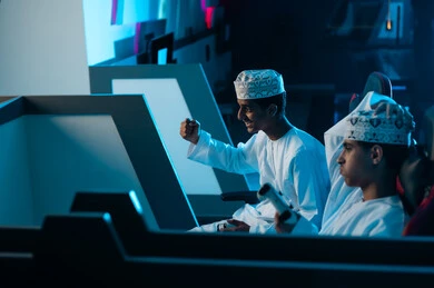 وضع اليد على الرأس بحزن وحسرة الخسارة , شاب عربي خليجي عماني يرفع قبضة يده لاعلى علامة على الفوز على صديقه , تعابير السعادة بالفوز , تعبير الحزن بالخسارة في اللعبة الالكترونية