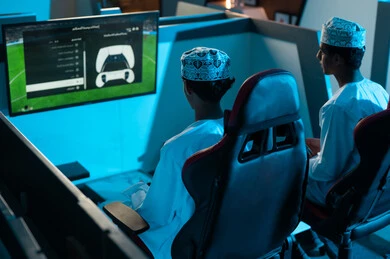 Determining the teams before the start of the game, two young Arab Gulf Omanis wearing white dishdasha and embroidered kumma are playing the famous electronic football game, youth recreational activities in the Sultanate of Oman.