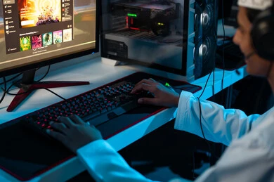 شاب عربي خليجي عماني يرتدي دشداشة بيضاء و كمة مطرزة يضع سماعة الرأس لسهولة التواصل مع الاصدقاء اثناء اللعب , مركز العاب الكترونية , النقر على لوحة المفاتيح