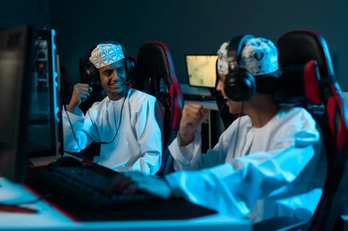 رجلان عربيان عمانيان خليجيان صغيران يرتديان الدشداشة البيضاء والكمة المطرزة ينظران لبعضهما بسعادة , رفع قبضة اليد لاعلى علامة على تحقيق الفوز , ايماءات الفرحة و السعادة ,