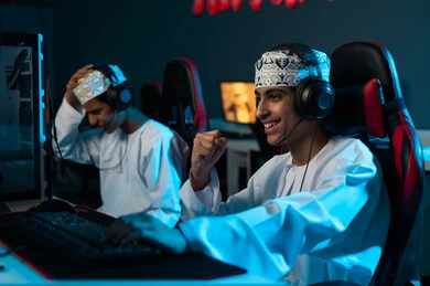 المنافسة بين الاصدقاء , شاب عربي خليجي عماني يرتدي الدشداشة البيضاء و الكمة المطرزة يرفع قبضة اليد لاعلى علامة على النصر , رجل عربي خليجي عماني يضع يده فوق رأسه اشارة الى الحزن و الحسرة , ايماءات السعادة بالفوز و الحزن للخسارة