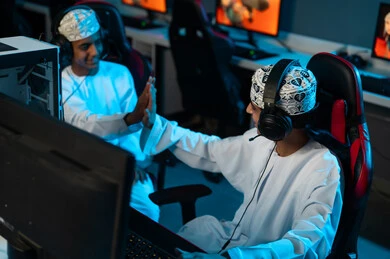 مصافحة الكفين في الاعلى اشارة الى الفوز , شابان عربيان خليجيان عمانيان يقضيان اللحظات الممتعة في مركز الالعاب الالكترونية , ايماءات السعادة و الابتسامة