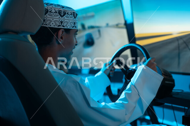 قضاء الاوقات الممتعة في مركز الالعاب الالكترونية , شاب عربي خليجي عماني يرتدي الدشداشة البيضاء و الكمة المطرزة يجلس في مقعد السائق , ايماءات السعادة و الفرحة