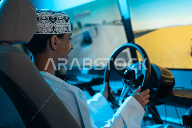 ايماءات الفرحة و الابتسامة اثناء النظر الي الشاشة , شاب عربي خليجي عماني يمسك عجلة القيادة بثبات , التركيز للفوز بالمركز الاول , صورة مقربة