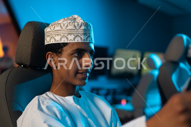 النظر للشاشة بتركيز و ثبات لتحقيق العامة الكاملة , رجل عربي خليجي عماني يرتدي دشداشة بيضاء و كمة مطرزة يجلس على مقعد ساثق سباق السيارات , ألعاب محاكاة الواقع الحقيقي , صورة مقربة