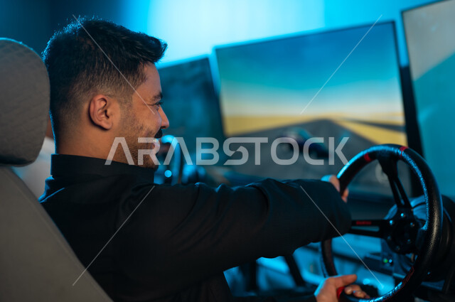 الفرحة العارمة و الحماس الشديد داخل مركز الالعاب الالكترونية , رجل عربي خليجي سعودي يرتدي الثوب الاسود يجلس امام الشاشة , قيادة لعبة السيارات باحترافية للفوز بالسباق ,