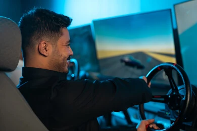 الفرحة العارمة و الحماس الشديد داخل مركز الالعاب الالكترونية , رجل عربي خليجي سعودي يرتدي الثوب الاسود يجلس امام الشاشة , قيادة لعبة السيارات باحترافية للفوز بالسباق ,