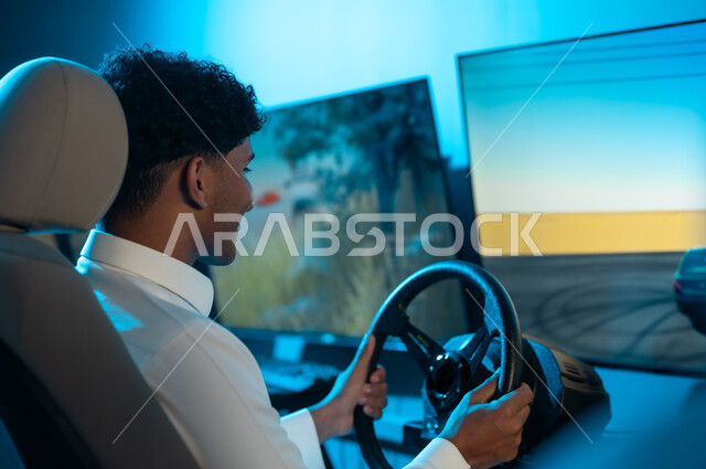 النظر بسعادة الي شاشة اللعبة , رجل عربي خليجي سعودي يرتدي الثوب الابيض يجلس خلف المقود , قضاء الاوقات الممتعة داخل مراكز الالعاب الااكترونية ,