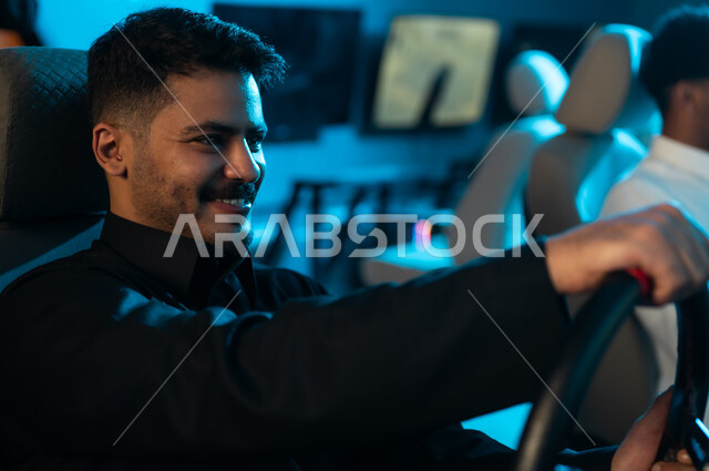 السعادة للفوز بالمركز الاول في لعبة السيارات , رجل عربي خليجي سعودي يرتدي الثوب الاسود يجلس خلف مقود اللعبة , محاكاة للقيادة الحقيقية , لحظات من المتعة و الوقت المسلي , ايماءات الابتسامة و الفرحة