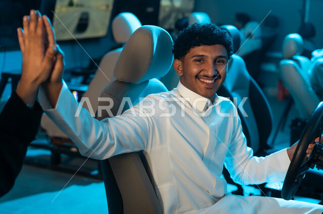 A Saudi Arabian Gulf man wearing a white thobe is shaking hands with his friend's hand high in the air as a sign of victory in the race, an enjoyable group game inside electronic gaming centers, gestures of joy and happiness.