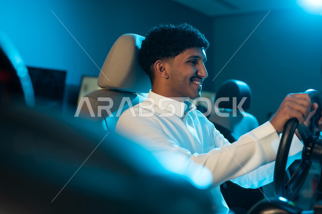 الجلوس خلف المقود و التركيز على الفوز في السباق , رجل عربي خليجي سعودي يرتدي الثوب الابيض ينظر الي الشاشة , ايماءات السعادة و الفرحة , صورة مقربة