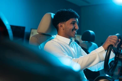 الجلوس خلف المقود و التركيز على الفوز في السباق , رجل عربي خليجي سعودي يرتدي الثوب الابيض ينظر الي الشاشة , ايماءات السعادة و الفرحة , صورة مقربة