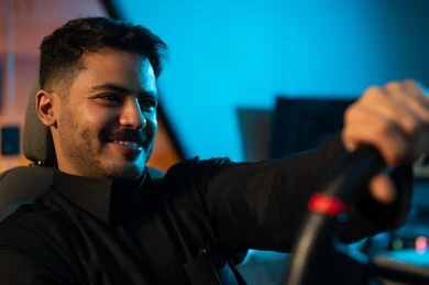 النظر الي شاشة اللعبة , رجل عربي خليجي سعودي يرتدي الثوب الاسود يمسك مقود السيارة جيداً , لعبة فردية و جماعية ممتعة , ايماءات السعادة و البهجة , صورة مقربة