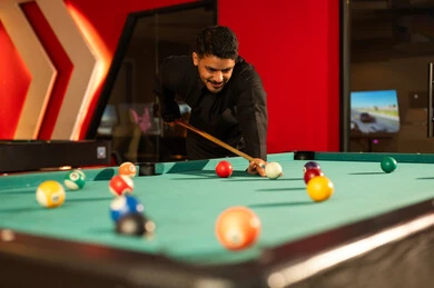 النظر الى الكرة البيضاء الصغيرة , رجل عربي خليجي سعودي يرتدي الثوب الاسود يقف امام طاولة البلياردو , تحريك الكرات الصغيرة الملونة و ادخالها في الجيوب الصغيرة و لعبة فردية او جماعيىة
