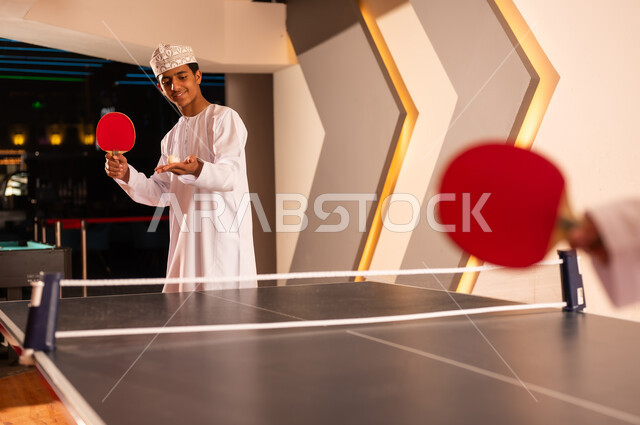 حمل الكرة الصغيرة البيضاء داخل كف اليد , شاب عربي خليجي عماني يرتدي الدشداشة البيضاء و الكمة المطرزة , الاستعداد لبدء اللعبة الحماسية , ايماءات السعادة , صورة مقربة