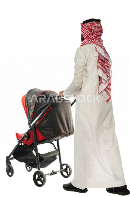 بورتريه من الخلف لرجل عربي خليجي سعودي يجرعربة الأطفال ، رابطة الأبوة ، ترابط عاطفي ، مفهوم الأسرة السعيدة ، نزهة و جولة عائلية ، قضاء أوقات عائلية ممتعة