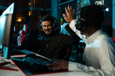 تعابير السعادة البالغة و الحماس الزائد اثناء اللعب في مركز الالعاب الالكترونية , رجلان عربان خليجيان سعوديان يرتديان الثوب الابيض و الثوب الاسود يضربان كفهما عالياً علامة على الفوز و تحقيق الانتصار , ايماءات السعاة و الابتسامة , النظر لبعضهما الاخر