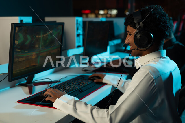 النظر الي شاشة الحاسب بابتسامة و سعادة , رجل عربي خليجي سعودي يرتدي الثوب الابيض ينقر على لوحة المفاتيح , اللعب بشغف و حماس , ايماءات السعادة و البهجة