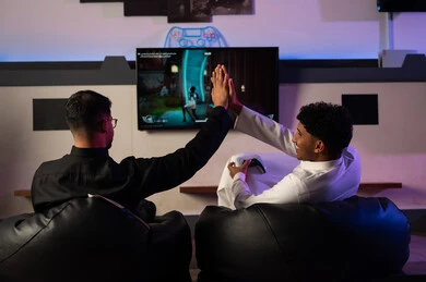 أوقات ممتعة في مركز الالعاب الالكترونية بين الشباب , رجلان عربيان خليجيان سعوديان يرتديان ثوب ابيض و ثوب اسود يضربان الكف بالكف عالياً علامة على النصر و تحقيق الفوز , ايماءات البهجة و الفرحة ,