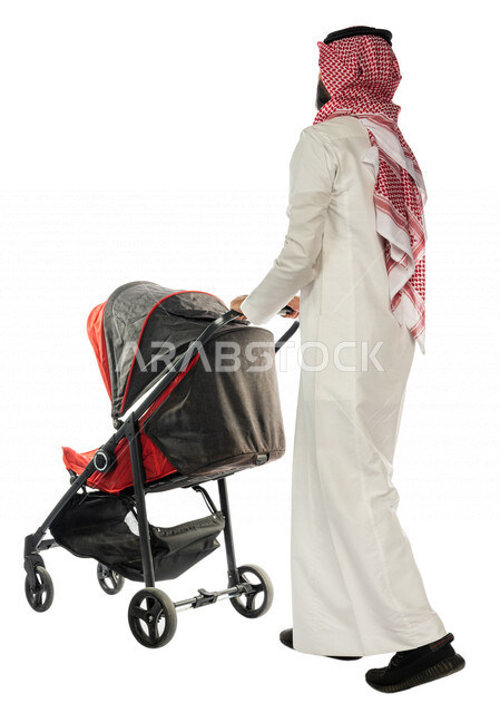 بورتريه من الخلف لرجل عربي خليجي سعودي يجرعربة الأطفال ، رابطة الأبوة ، ترابط عاطفي ، مفهوم الأسرة السعيدة ، نزهة و جولة عائلية ، قضاء أوقات عائلية ممتعة