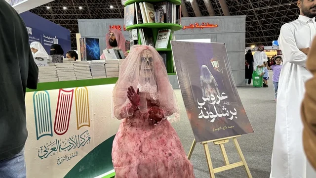 Arab Literature Center, a depiction of a figure wearing a pink wedding dress, a promotional tool for a novel titled "Bride of Barcelona," International Book Fair in Jeddah on December 16, 2025, famous cultural landmarks and tourist attractions in the Kingdom of Saudi Arabia, attracting and drawing tourists from around the world, Riyadh Season events.