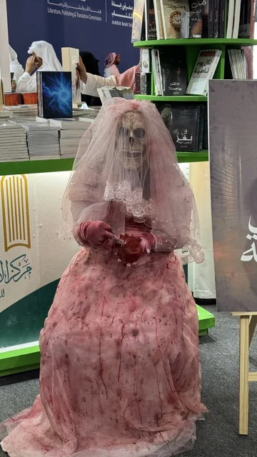 معرض الكتاب الدولي في جدة 16 من ديسمبر 2025 ، مركز الأدب العربي، تصوير لمجسم يرتدي فستان زفاف وردي اللون، أداة ترويجية لرواية بعنوان "عروس برشلونة"، المعالم والأماكن السياحية الثقافية المشهورة فى المملكة العربية السعودية، استقطاب وجذب السياح من أنحاء العالم ، فعاليات موسم الرياض