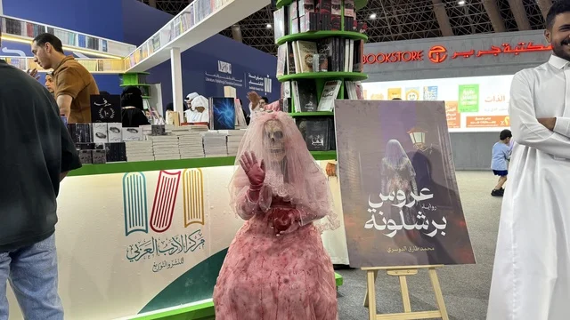 المعالم والأماكن السياحية الثقافية المشهورة فى المملكة العربية السعودية، مركز الأدب العربي، تصوير لمجسم يرتدي فستان زفاف وردي اللون، أداة ترويجية لرواية بعنوان "عروس برشلونة"، معرض الكتاب الدولي في جدة 16 من ديسمبر 2025 ، استقطاب وجذب السياح من أنحاء العالم ، فعاليات موسم الرياض
