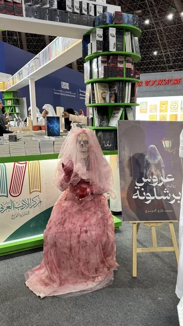 Riyadh Season events, Arab Literature Center, a photo of a mannequin wearing a pink wedding dress, a promotional tool for a novel titled "Barcelona Bride," International Book Fair in Jeddah on December 16, 2025, famous cultural landmarks and tourist attractions in the Kingdom of Saudi Arabia, attracting and drawing tourists from around the world.