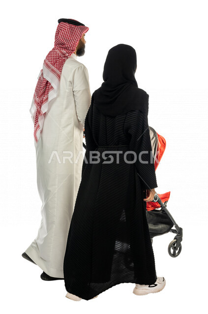 بورتريه من الخلف لرجل عربي خليجي سعودي يجرعربة الأطفال برفقة زوجته ، ترابط عاطفي ، مفهوم الأسرة السعيدة ، نزهة و جولة عائلية ، قضاء أوقات عائلية ممتعة