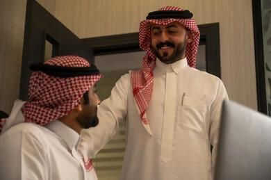 Monitoring the workflow and discussing technical details, teamwork and the spirit of unity, teaching employees new methods of work to achieve the company's goals, two Arab Gulf colleagues from Saudi Arabia wearing the thobe and ghutrah are completing tasks via the computer.