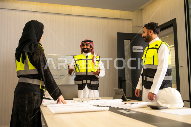 الإشراف على سير العمل الهندسي وفق الخطط الموضوعة، الشركات المختصة بورشات البناء والمقاولات، التخطيط ووضع المخططات المعمارية، مجموعة مهندسون عربيون خليجيون سعوديون يردتون الثوب التقليدي و سترة الحماية يعملون على مناقشة مخطط الإنشاء وتحديد القياسات بدقة داخل مقر الشركة