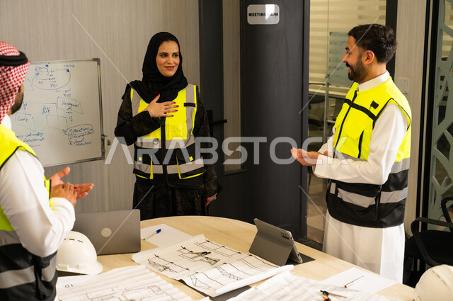 إظهار التقدير أثناء عرض الأفكار، مفهوم التحفيز والدعم في بيئة العمل, رجلان عربيان خليجيان سعوديان يرتدي الثوب التقليدي و  ستره الحماية يقومان بالتصفيق لزميلتهم