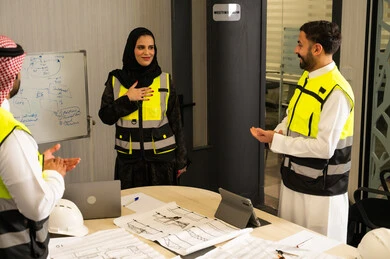 إظهار التقدير أثناء عرض الأفكار، مفهوم التحفيز والدعم في بيئة العمل, رجلان عربيان خليجيان سعوديان يرتدي الثوب التقليدي و  ستره الحماية يقومان بالتصفيق لزميلتهم