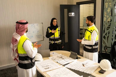 مفهوم التحفيز والدعم في بيئة العمل, إظهار التقدير أثناء عرض الأفكار, رجلان عربيان خليجيان سعوديان يرتدي الثوب التقليدي و  ستره الحماية يقومان بالتصفيق