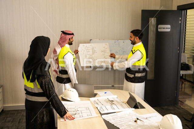 الإشراف على تطبيق الخطط الهندسية المعتمدة، الشركات المتخصصة في ورشات البناء والمقاولات، التخطيط وإعداد الرسومات المعمارية، مجموعة مهندسون عرب خليجيون سعوديون يعملون على مناقشة مخطط الإنشاء وتحديد القياسات بدقة داخل مقر الشركة