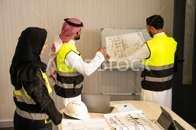 متابعة تنفيذ الخطط الهندسية الموضوعة، الشركات المختصة بورشات البناء والمقاولات، التخطيط ووضع المخططات المعمارية، مجموعة مهندسون عربيون خليجيون سعوديون يعملون على مناقشة مخطط الإنشاء وتحديد القياسات بدقة داخل مقر الشركة