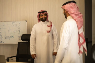 تبادل الخبرات بين الزملاء، التركيز والعمل المتقن, الحوارات والنقاشات ضمن الفريق,تطوير الاعمال والشركات, اجتماع عمل وانجاز المشاريع, مناقشة الخطط وشرح مهام الاعمال, رجلان عربيان خليجين سعوديان يرتديان الثوب الابيض و الشماغ يقومان بالمناقشة ، ايماءات السعادة و السرور