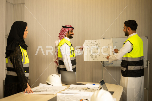 Monitoring and following up on construction operations, the concept of engineering and construction project management, studying the plan and the project, a profession and job for young engineers, two Arab Gulf engineers from Saudi Arabia wearing white thobes and safety vests carrying the engineering plan accompanied by their colleague.